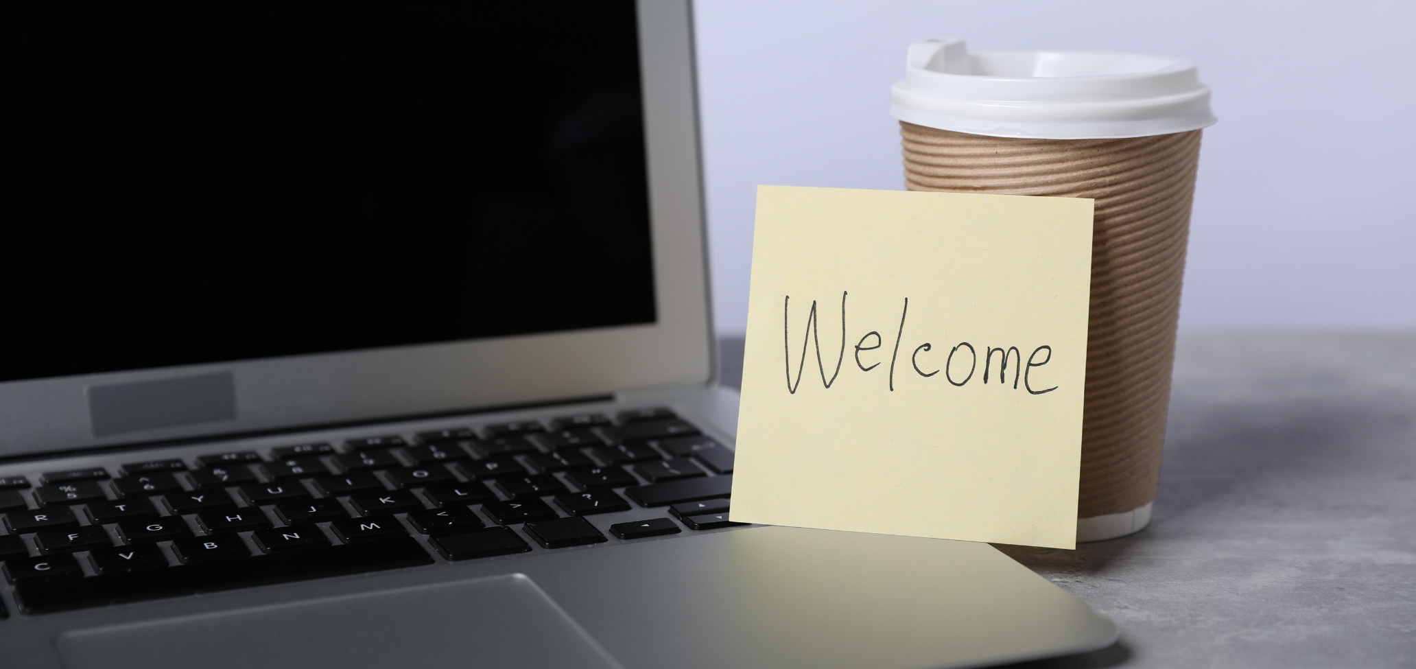 welcome note beside laptop and coffee