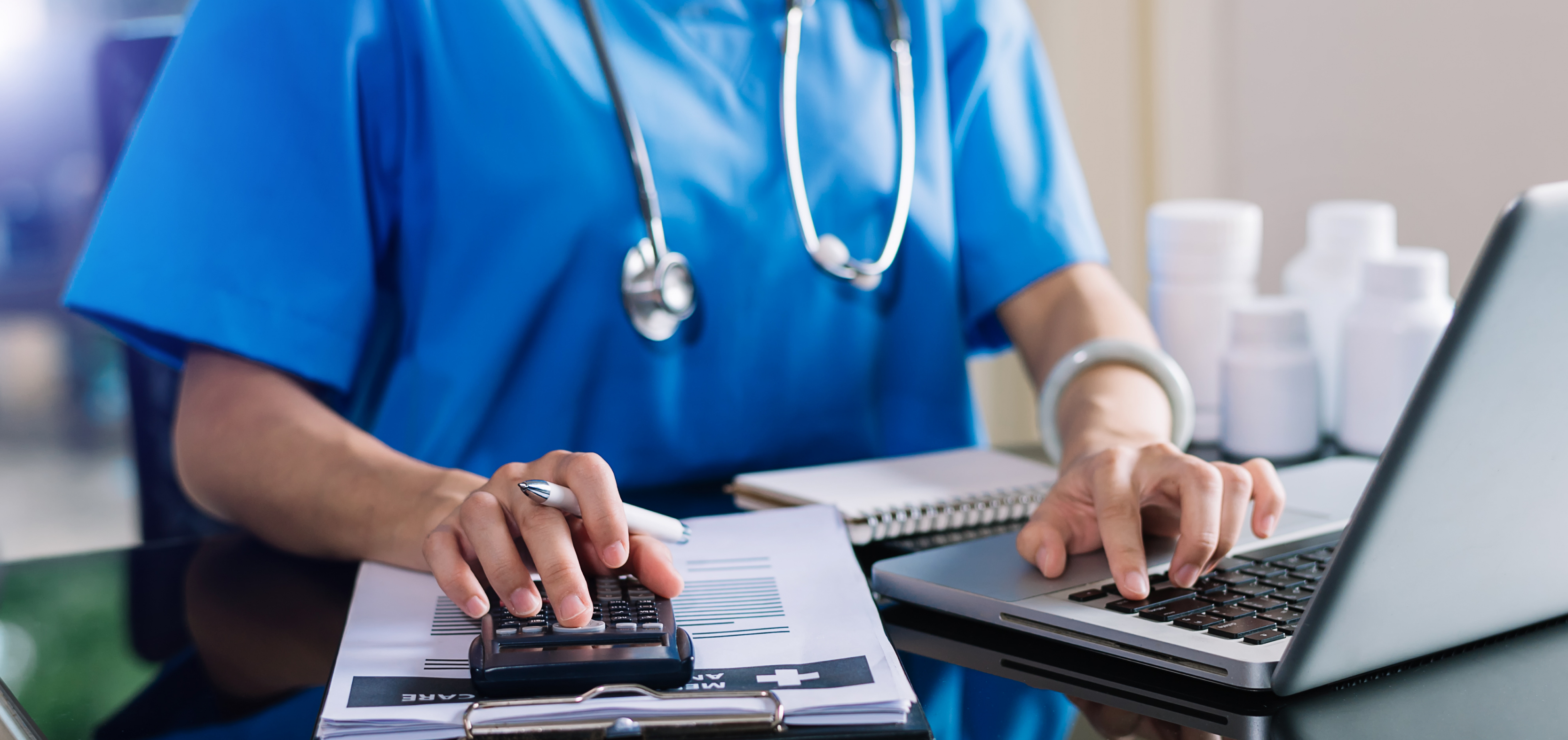 Healthcare professional reviewing finances with a calculator and laptop