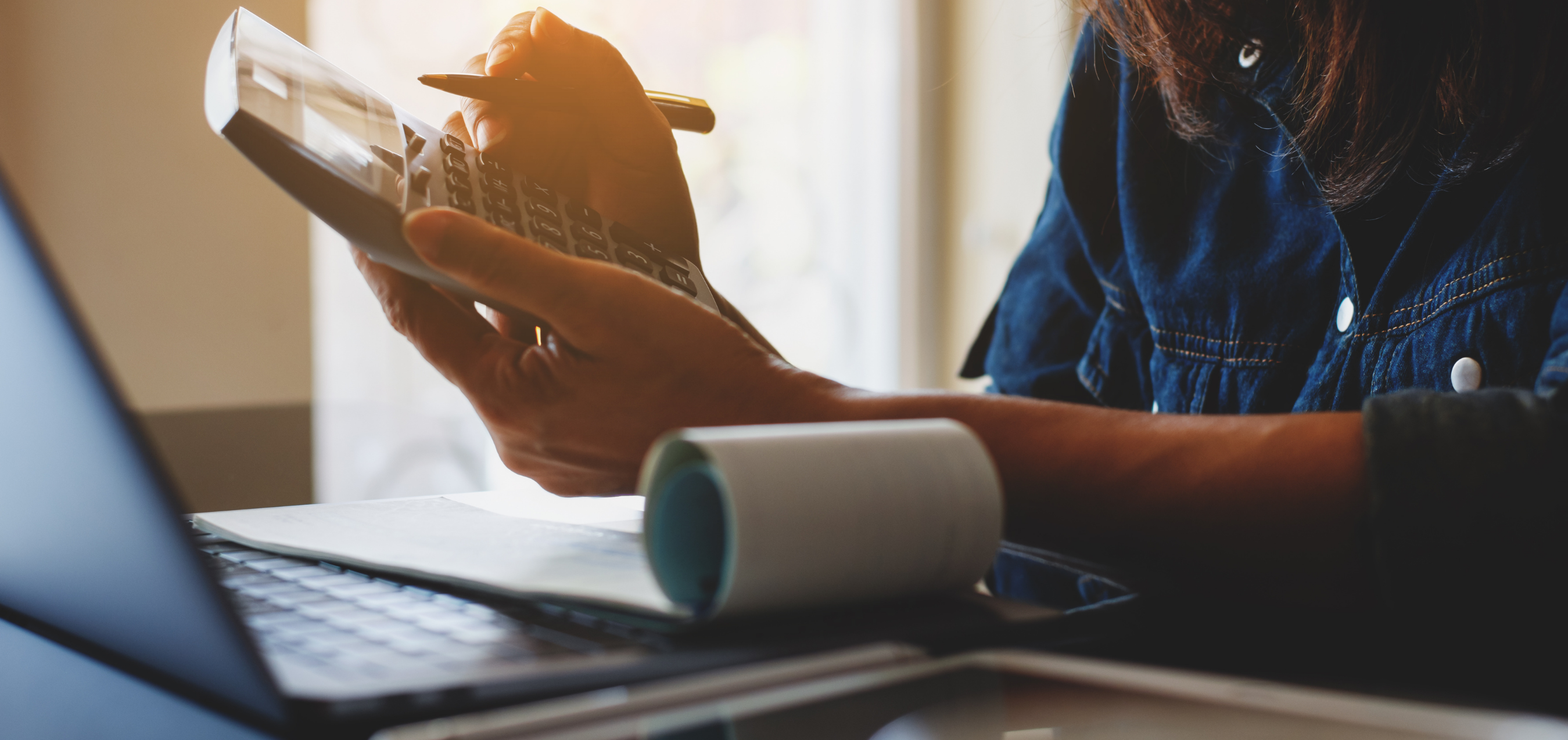 person using a calculator beside payroll documents